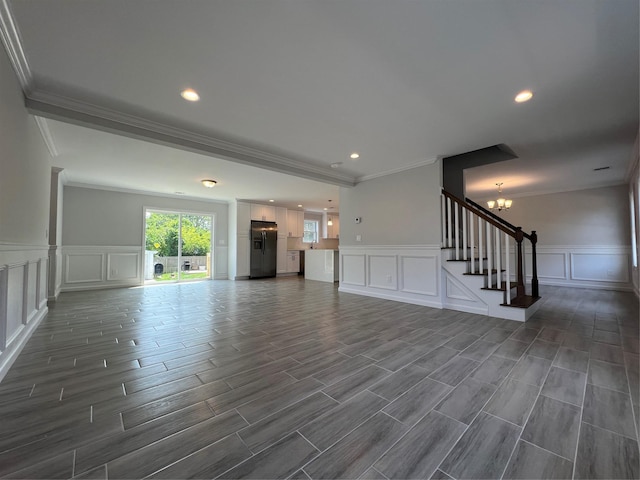 96 Baybright Dr, Shirley, NY 11967 - unfurnished living room featuring a decorative wall, crown molding, stairs, a wainscoted wall, and a chandelier