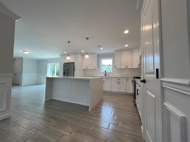 96 Baybright Dr, Shirley, NY 11967 - kitchen featuring fridge with ice dispenser, a kitchen island, white cabinetry, a decorative wall, and ornamental molding