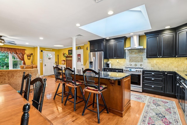 11 Kim Ave, Smithtown, NY 11787 - kitchen with appliances with stainless steel finishes, wall chimney exhaust hood, ornate columns, a center island, and dark cabinetry