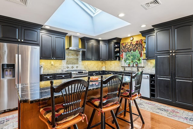 11 Kim Ave, Smithtown, NY 11787 - kitchen with wall chimney range hood, appliances with stainless steel finishes, a skylight, dark stone countertops, and recessed lighting