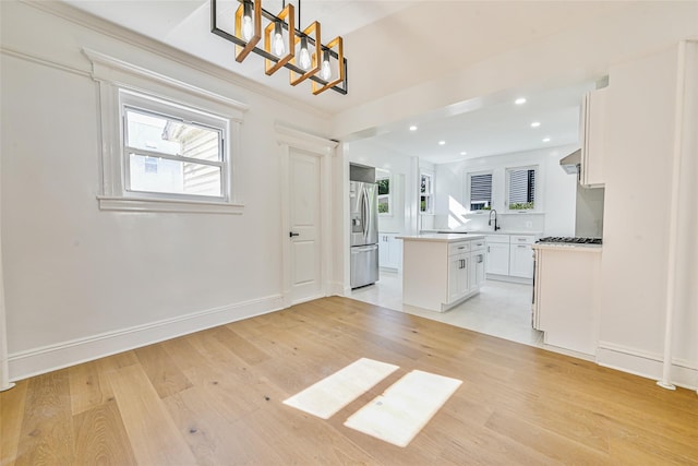 108 N Forest Ave, Rockville Centre, NY 11570 - kitchen with stainless steel fridge, light wood-style floors, a kitchen island, white cabinets, and recessed lighting