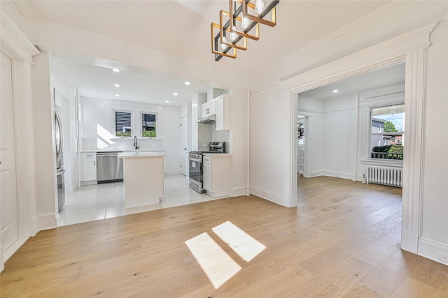 108 N Forest Ave, Rockville Centre, NY 11570 - unfurnished living room featuring radiator, plenty of natural light, light wood-style flooring, recessed lighting, and ornamental molding