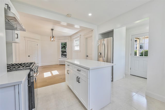 108 N Forest Ave, Rockville Centre, NY 11570 - kitchen featuring stainless steel appliances, radiator, under cabinet range hood, white cabinets, and light countertops