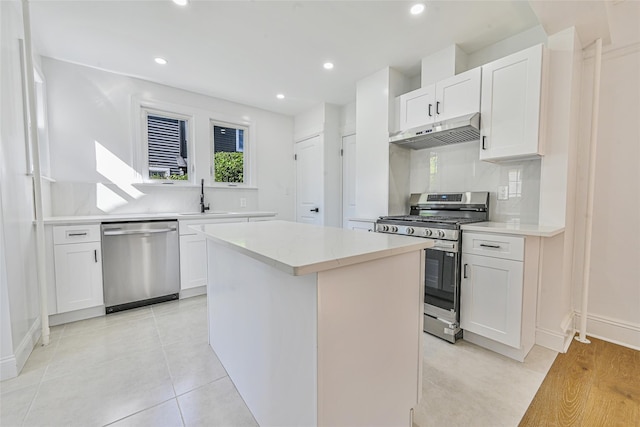 108 N Forest Ave, Rockville Centre, NY 11570 - kitchen with stainless steel appliances, under cabinet range hood, a kitchen island, tasteful backsplash, and white cabinets