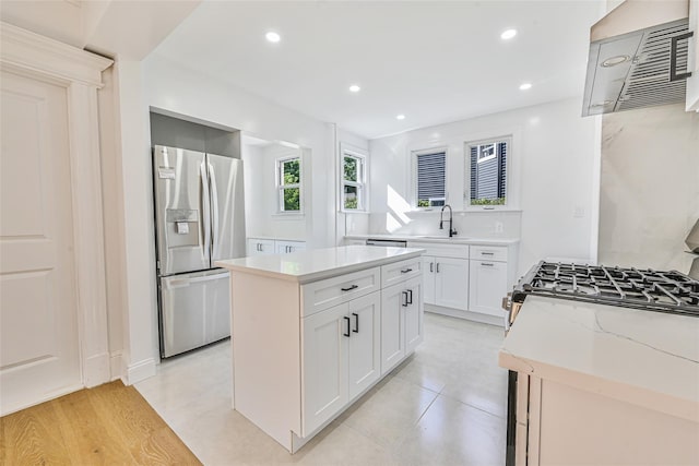 108 N Forest Ave, Rockville Centre, NY 11570 - kitchen featuring stainless steel fridge, ventilation hood, gas range, a kitchen island, and white cabinets