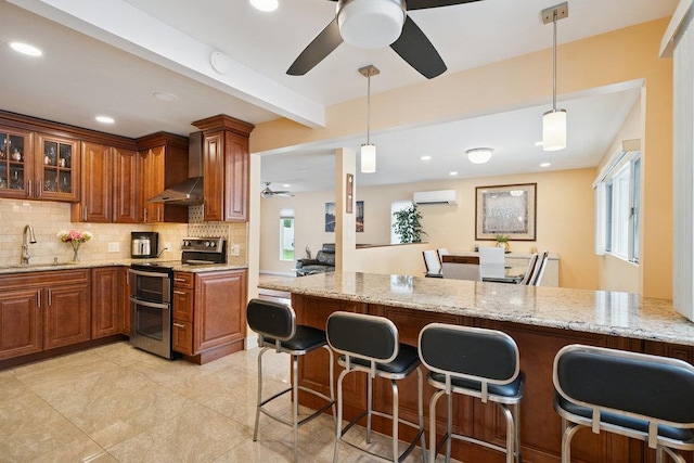 11 Sunrise St, Plainview, NY 11803 - kitchen featuring double oven range, wall chimney range hood, ceiling fan, an AC wall unit, and a breakfast bar