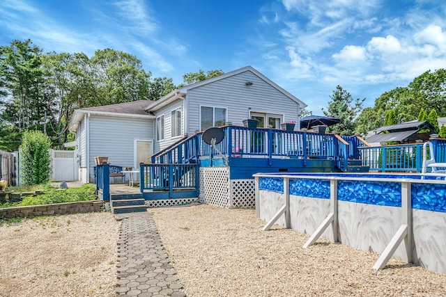 43 Ranch Dr, Shirley, NY 11967 - back of house featuring a wooden deck, a gate, and an outdoor pool