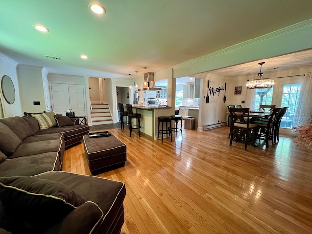 27 W Ave, Putnam Valley, NY 10579 - living room featuring crown molding, a chandelier, baseboard heating, light wood-type flooring, and stairs