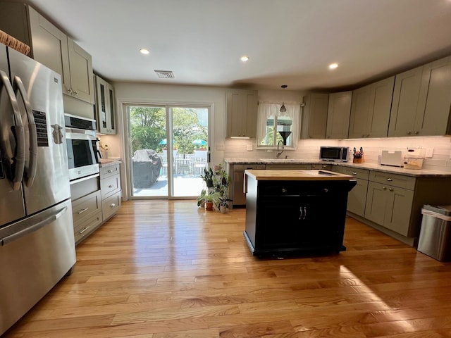 27 W Ave, Putnam Valley, NY 10579 - kitchen featuring stainless steel appliances, light countertops, backsplash, light wood-style floors, and a kitchen island
