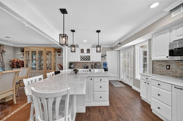 28 Lapin Ln, Blauvelt, NY 10913 - kitchen featuring stainless steel microwave, backsplash, white cabinetry, crown molding, and light stone countertops