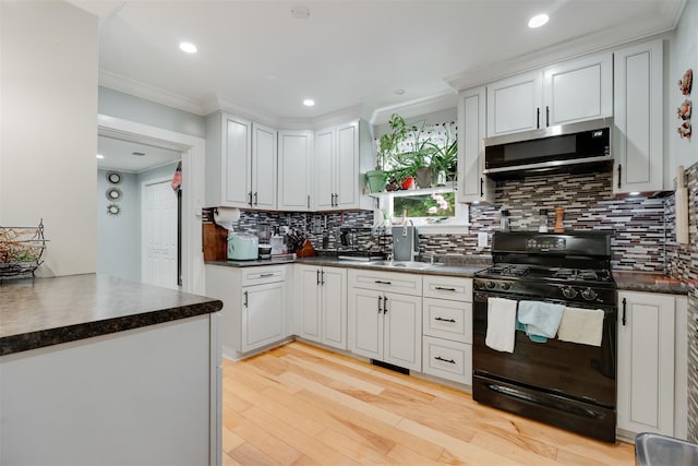 110 Pine Ave, Ossining, NY 10562 - kitchen with gas stove, stainless steel microwave, ornamental molding, dark countertops, and light wood-style flooring