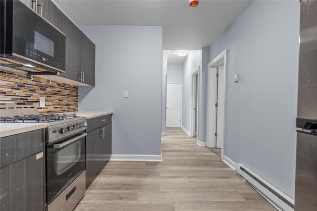 123 Elm St, Yonkers, NY 10701 - kitchen with black microwave, gas stove, a baseboard radiator, light wood-style floors, and backsplash