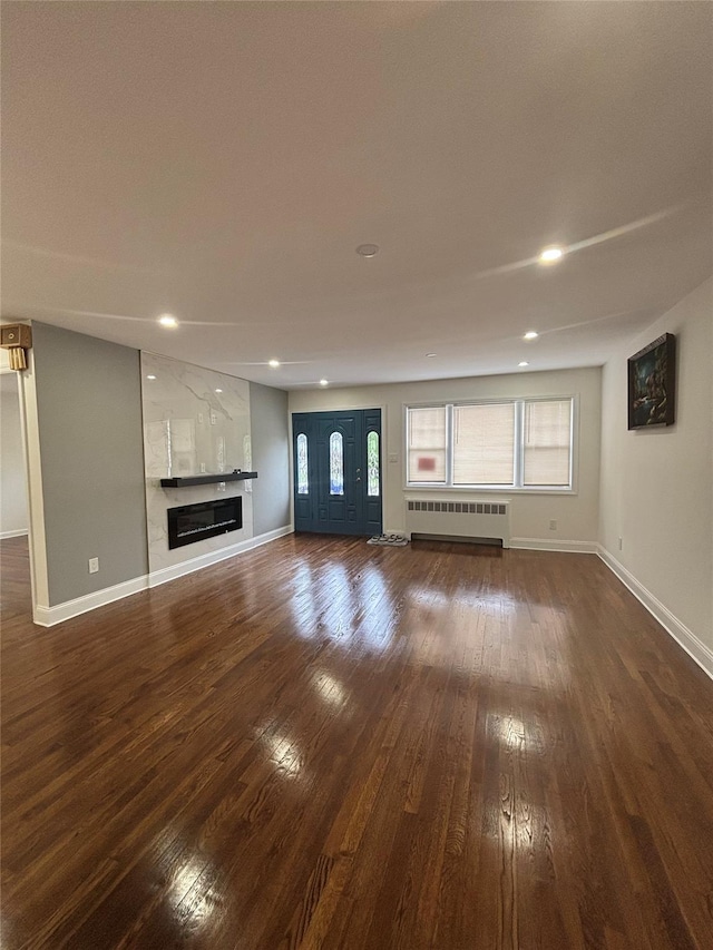868 Oliver Ave, Westbury, NY 11590 - unfurnished living room with radiator, hardwood / wood-style flooring, recessed lighting, and a large fireplace