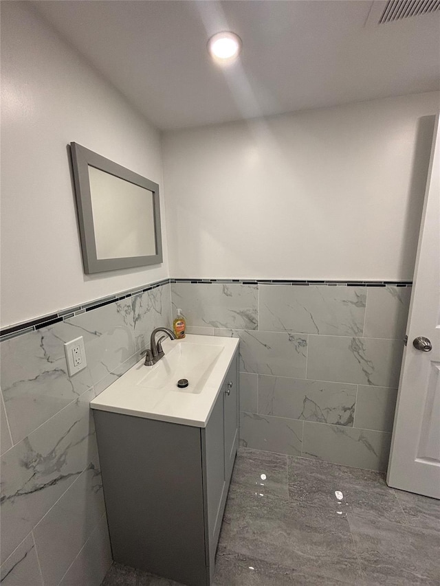 868 Oliver Ave, Westbury, NY 11590 - bathroom with marble look tile flooring, tile walls, vanity, and wainscoting