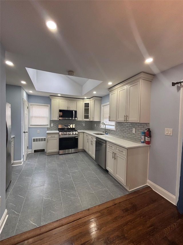 868 Oliver Ave, Westbury, NY 11590 - kitchen featuring appliances with stainless steel finishes, radiator, tasteful backsplash, light countertops, and healthy amount of natural light