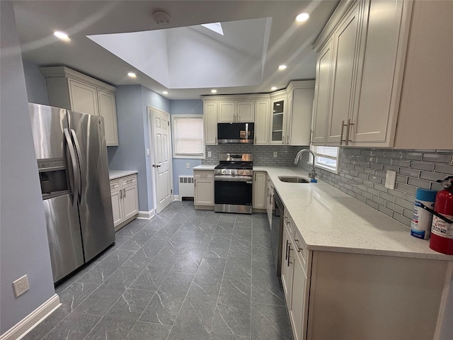 868 Oliver Ave, Westbury, NY 11590 - kitchen featuring stainless steel appliances, radiator heating unit, decorative backsplash, a skylight, and recessed lighting