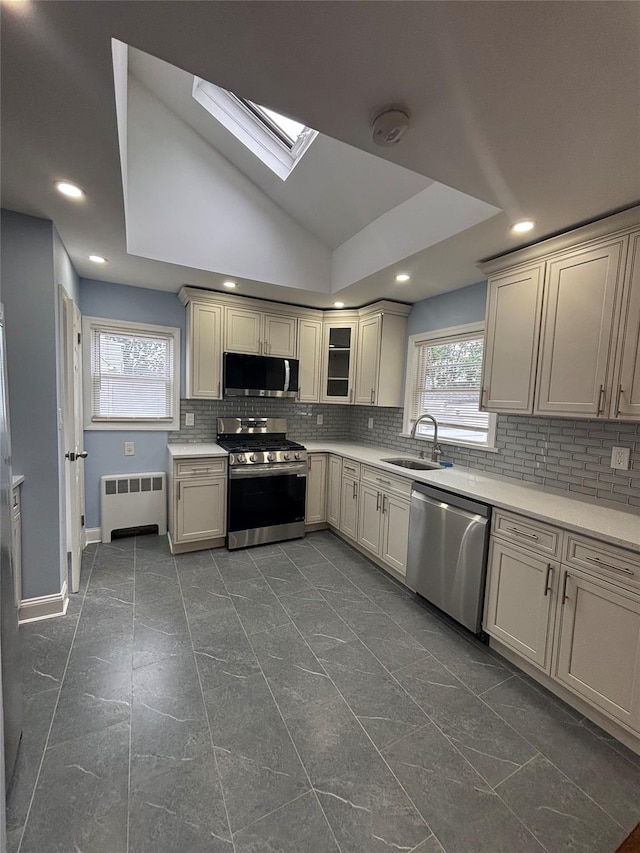 868 Oliver Ave, Westbury, NY 11590 - kitchen featuring stainless steel appliances, radiator, a skylight, backsplash, and recessed lighting