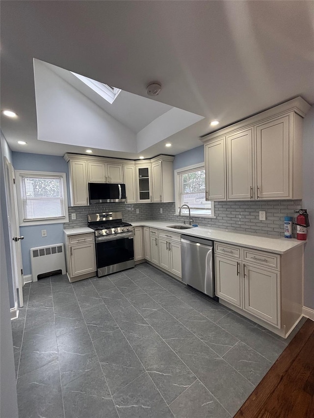 868 Oliver Ave, Westbury, NY 11590 - kitchen with stainless steel appliances, radiator heating unit, tasteful backsplash, light countertops, and recessed lighting