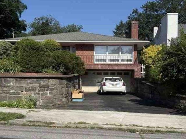 937 Mckinley St, Peekskill, NY 10566 - view of front of house with a garage, asphalt driveway, and a chimney