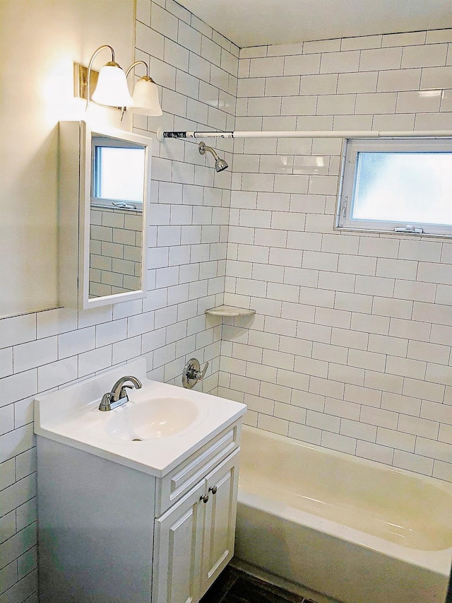 114 Park Ave, Mount Vernon, NY 10550 - bathroom featuring vanity, washtub / shower combination, tile walls, healthy amount of natural light, and backsplash