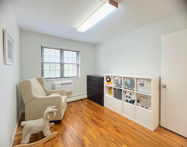 22035 67th Ave Unit C, Bayside, NY 11364 - living area featuring a wall mounted AC, baseboard heating, and wood finished floors