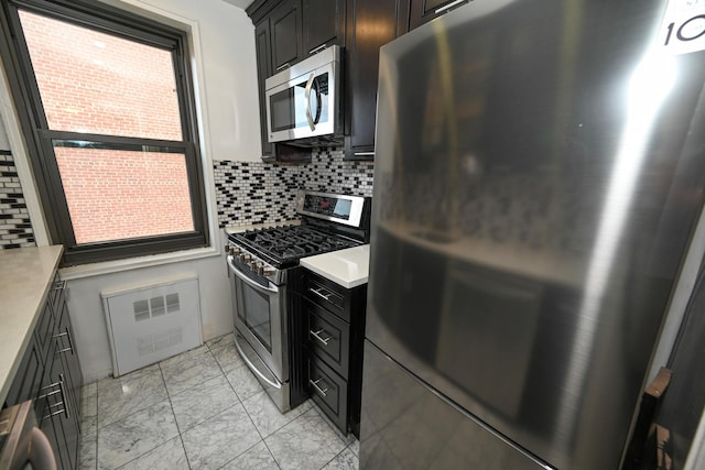 84-01 Main St Unit 410, Briarwood, NY 11435 - kitchen featuring stainless steel appliances, light marble finish flooring, radiator, light countertops, and backsplash