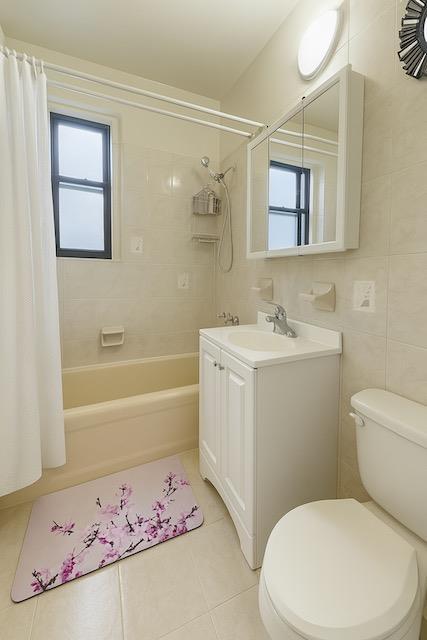 3545 81st St Unit C2, Jackson Heights, NY 11372 - bathroom featuring tile patterned flooring, shower / tub combo with curtain, vanity, and tile walls
