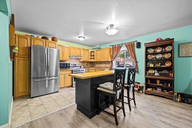 1935 Holland Ave, Bronx, NY 10462 - kitchen with stainless steel appliances, butcher block counters, glass insert cabinets, a breakfast bar, and backsplash
