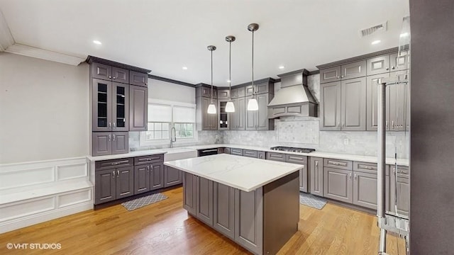 60 E Minerva Rd, Lindenhurst, NY 11757 - kitchen featuring custom exhaust hood, crown molding, a center island, glass insert cabinets, and gray cabinets