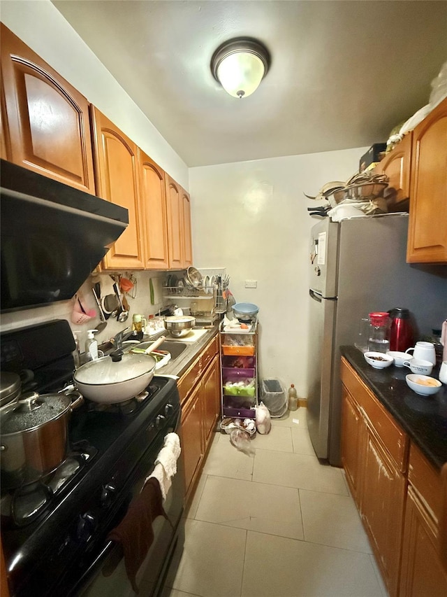138-70 Elder Ave Unit 3A, Flushing, NY 11355 - kitchen with black range with gas stovetop, light tile patterned flooring, freestanding refrigerator, dark countertops, and brown cabinets