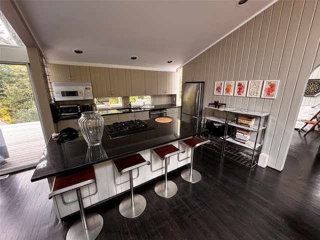 487 Tarpon Walk, Fire Island Pines, NY 11782 - kitchen featuring appliances with stainless steel finishes, dark countertops, ornamental molding, dark wood-style flooring, and a breakfast bar area