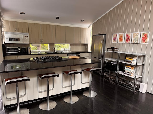487 Tarpon Walk, Fire Island Pines, NY 11782 - kitchen with appliances with stainless steel finishes, dark countertops, dark wood-style floors, a kitchen breakfast bar, and wood walls