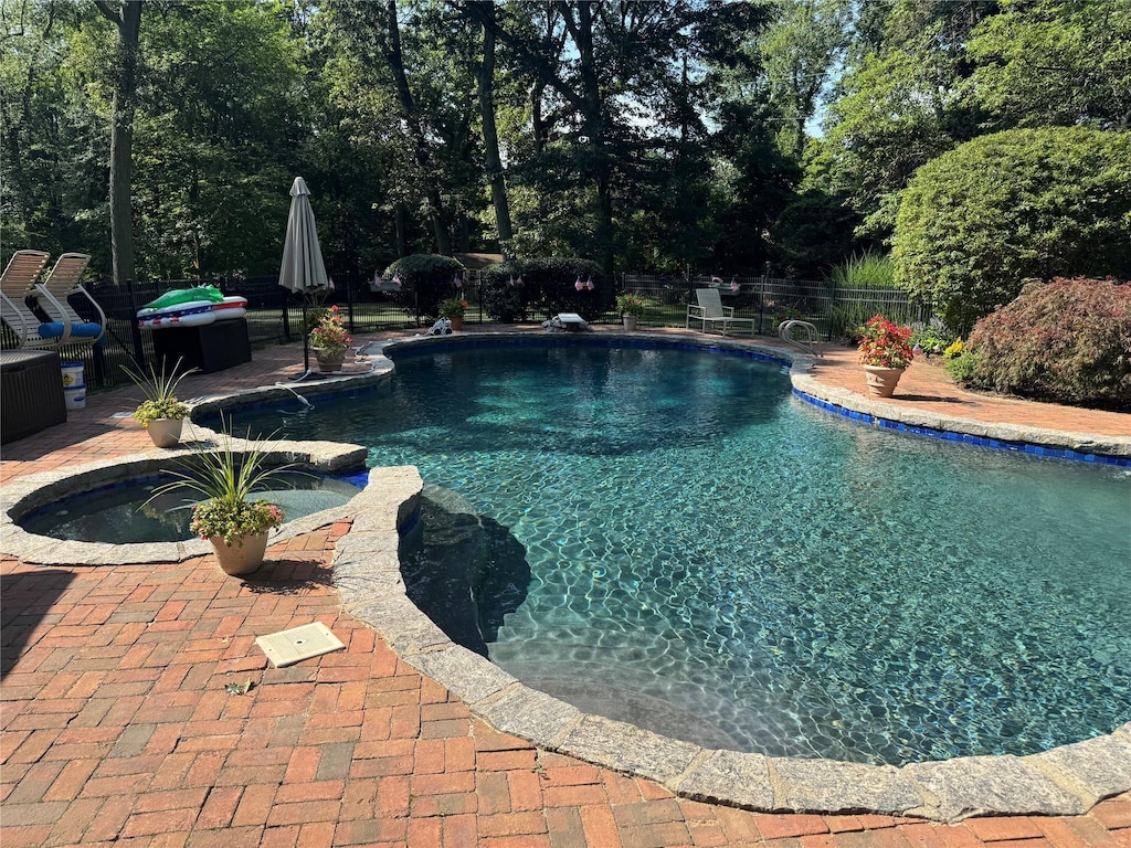 8 Rolling Dr, Brookville, NY 11545 - view of swimming pool featuring a patio, a fenced backyard, a pool with connected hot tub, and view of wooded area