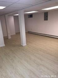 168-03 Cryders Ln, Whitestone, NY 11357 - finished below grade area featuring a baseboard heating unit, a paneled ceiling, wood finished floors, and electric panel