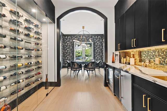 2 Maple Way, Woodbury, NY 11797 - wine area featuring light wood-style flooring, bar with sink, beverage cooler, and arched walkways
