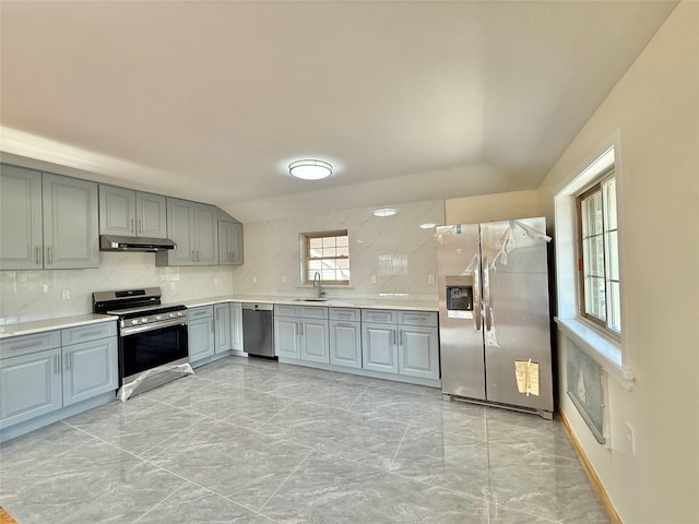 1604 Robertson Pl, Bronx, NY 10465 - kitchen with stainless steel appliances, under cabinet range hood, gray cabinetry, light marble finish flooring, and tasteful backsplash