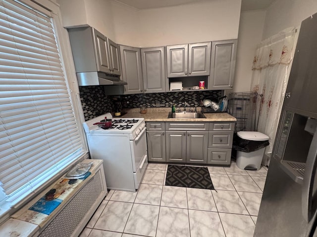 1492 E 45th St, Brooklyn, NY 11234 - kitchen featuring gray cabinets, white gas stove, under cabinet range hood, light tile patterned flooring, and light countertops
