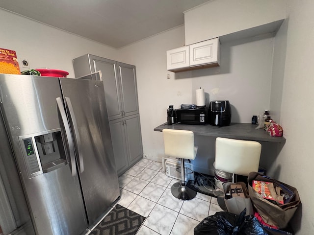 1492 E 45th St, Brooklyn, NY 11234 - kitchen with stainless steel fridge, black microwave, an office area, light tile patterned floors, and white cabinetry