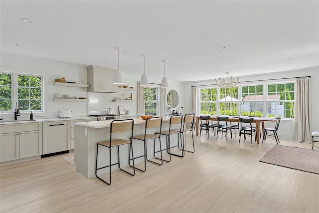 63 Armande St, Southampton, NY 11968 - kitchen with dishwasher, open shelves, a breakfast bar, light wood-style floors, and a chandelier