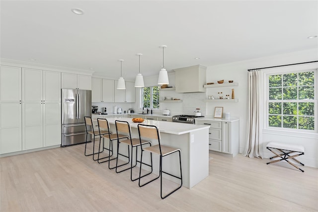 63 Armande St, Southampton, NY 11968 - kitchen with appliances with stainless steel finishes, open shelves, light wood-style flooring, a breakfast bar area, and crown molding