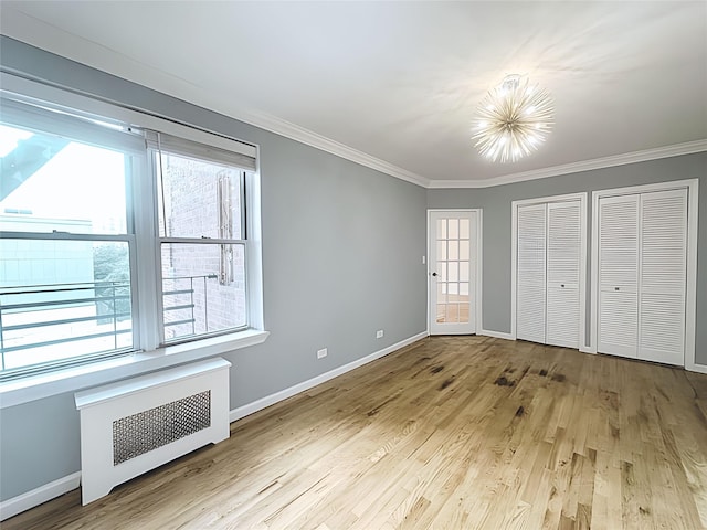 800 Grand Concourse Unit 2Js, Bronx, NY 10451 - unfurnished bedroom with radiator, ornamental molding, a chandelier, light wood-style flooring, and multiple closets