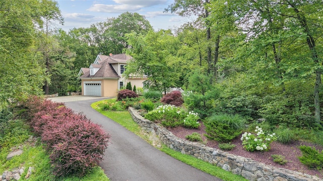 150 Hortontown Rd, Carmel, NY 10512 - view of front of house featuring driveway, an attached garage, stucco siding, a wooded view, and a chimney