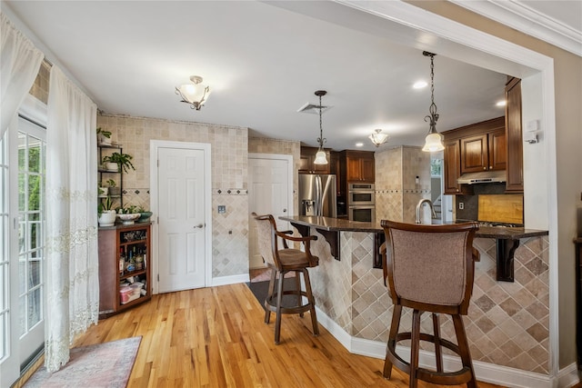 150 Hortontown Rd, Carmel, NY 10512 - kitchen featuring stainless steel appliances, dark countertops, a breakfast bar area, under cabinet range hood, and a peninsula
