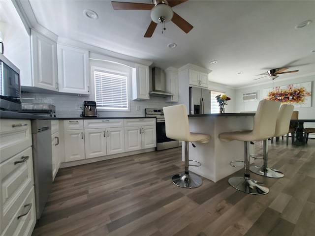 1336 Coates Ave, Holbrook, NY 11741 - kitchen featuring stainless steel appliances, ceiling fan, wall chimney range hood, a breakfast bar area, and dark countertops