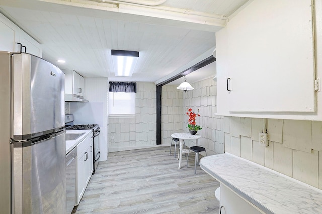 58 Wawayanda Ave, Middletown, NY 10940 - kitchen featuring stainless steel appliances, under cabinet range hood, white cabinetry, light countertops, and light wood finished floors