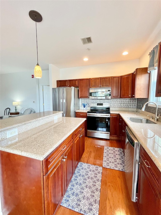 936 Tower Ridge Cir, Middletown, NY 10941 - kitchen with stainless steel appliances, light wood-style floors, pendant lighting, light stone countertops, and decorative backsplash