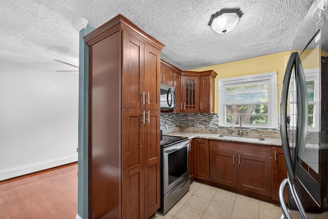 2710 S Rd Unit A4, Poughkeepsie, NY 12601 - kitchen with stainless steel appliances, a textured ceiling, light stone counters, decorative backsplash, and glass insert cabinets