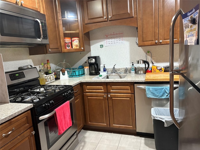 132 Weatherby Ln Unit 132, Central Islip, NY 11722 - kitchen featuring appliances with stainless steel finishes, light tile patterned flooring, glass insert cabinets, and brown cabinetry