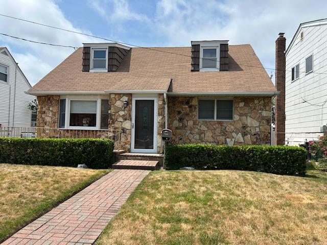862 Peninsula Blvd, Woodmere, NY 11598 - cape cod-style house featuring stone siding, a front yard, and roof with shingles