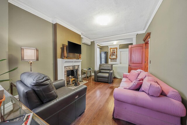 65 Granite St, Brooklyn, NY 11207 - living area with crown molding, wood-type flooring, a fireplace, a wall mounted air conditioner, and a textured ceiling